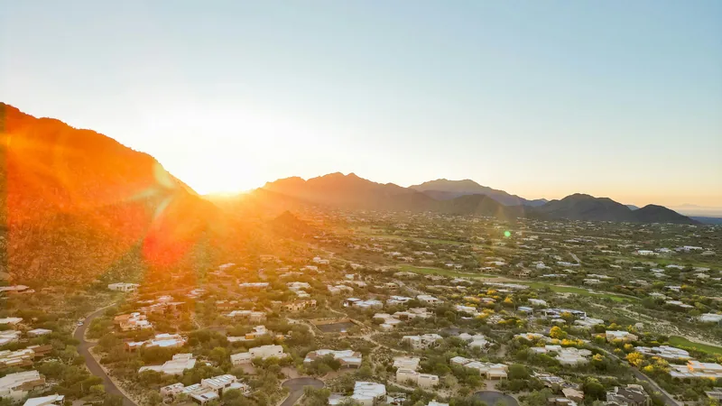 Low sun over a desert neighborhood and mountains, seen from above
