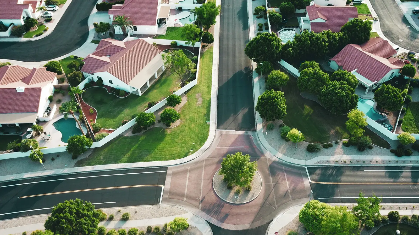 Aerial view of homes with tile roofs, pools and landscaping along curving suburban streets