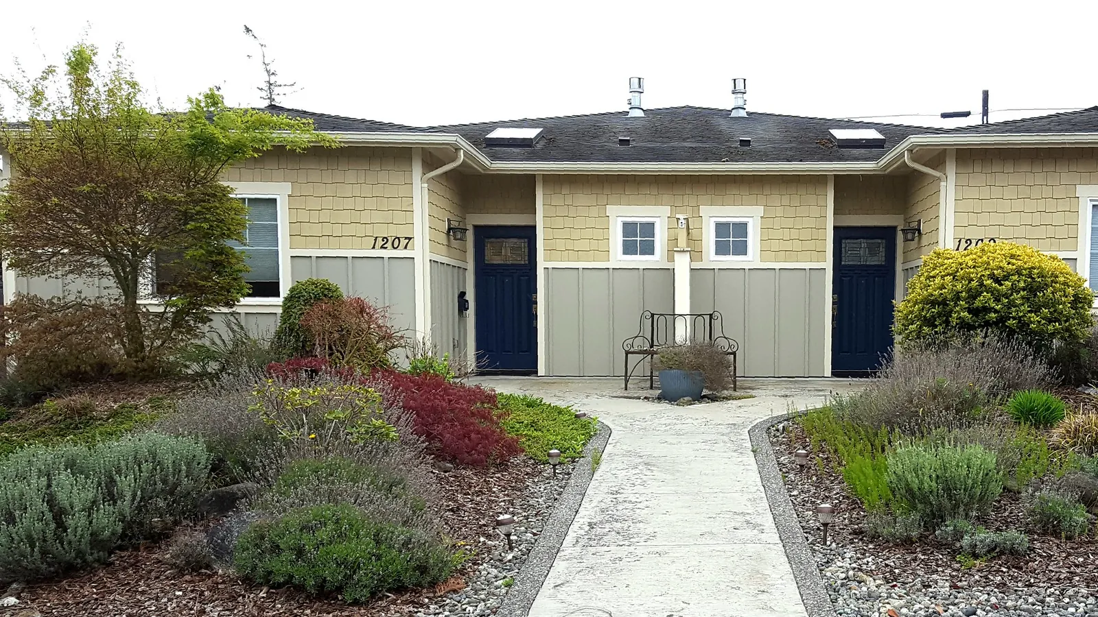 A single-story duplex with two front doors and a landscaped front yard