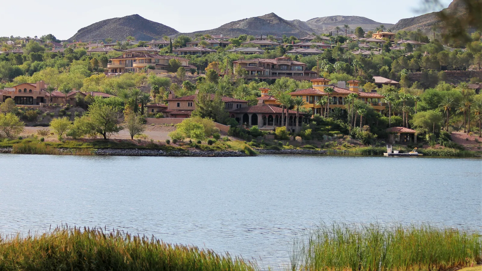 Large homes among trees on a hillside above a lake at Lake Las Vegas