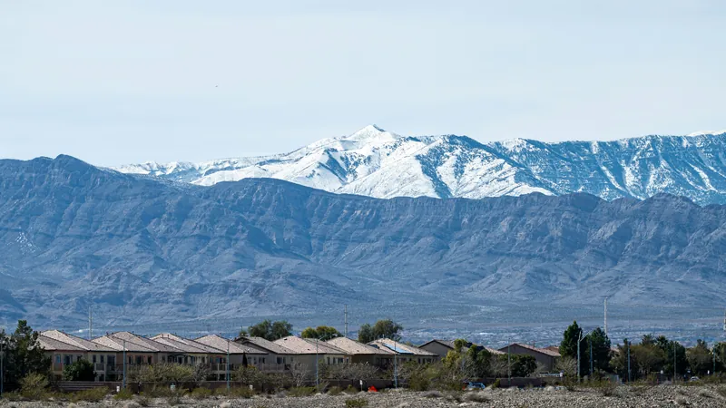 Row of houses in front of a desert valley with a snow-capped mountain range behind