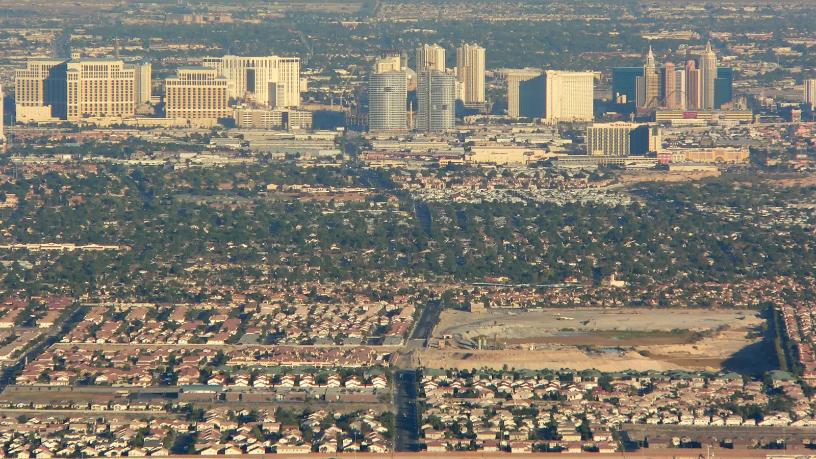 Aerial view of residential neighborhoods in the Las Vegas Valley with the Strip skyline in the distance