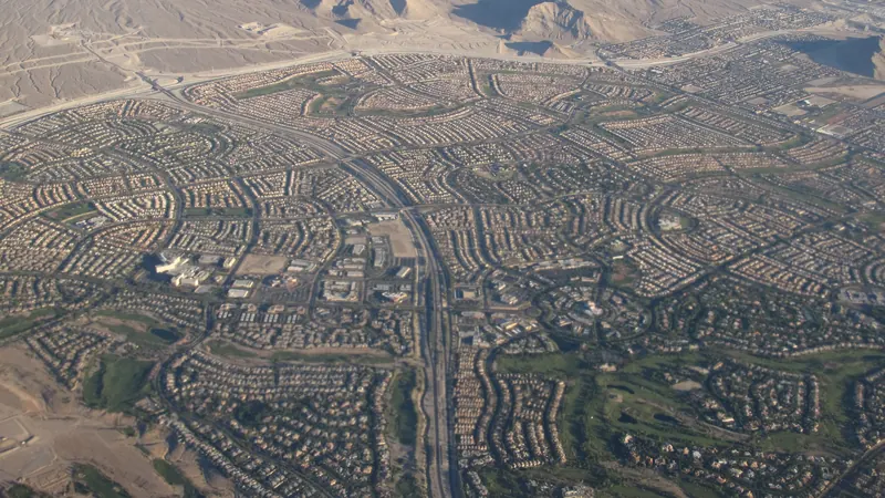 Aerial view of curving residential streets, green open space and desert hills in Summerlin