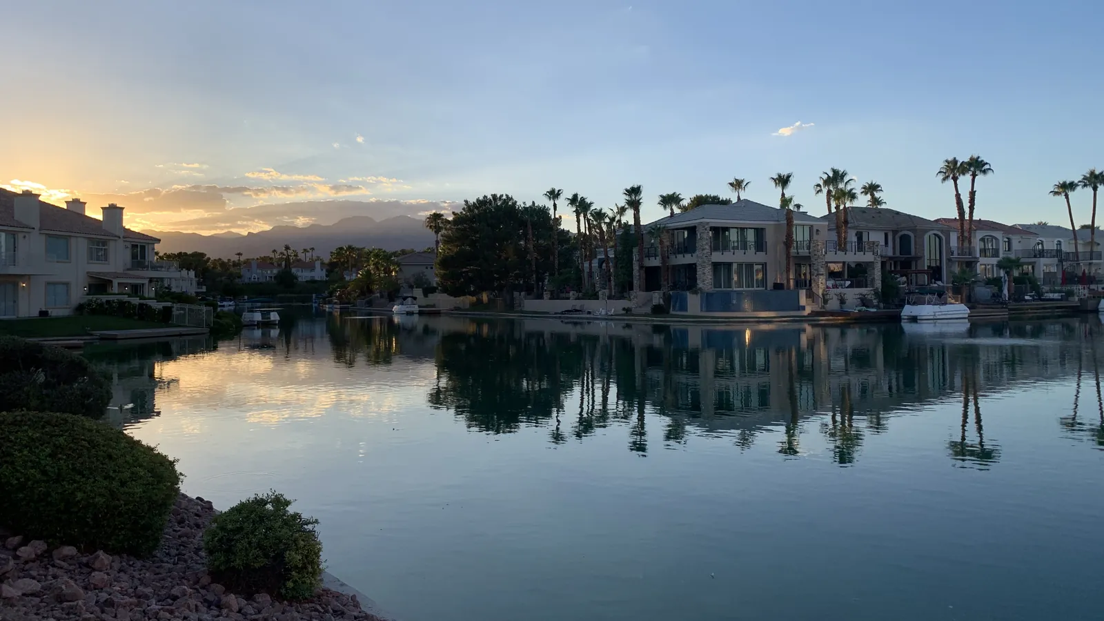 Waterfront homes and palm trees reflected in a lake at dusk in The Lakes, Las Vegas
